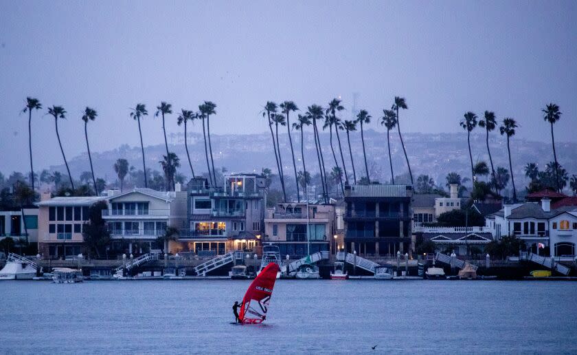 Long Beach, CA - February 21: A windsurfer takes advantage of cold, gusty winds kicking up as a winter storm approaches Southern Calfornia at dusk in Alamitos Bay in Long Beach Tuesday, Feb. 21, 2023. A winter storm warning remains in effect from 7pm Tuesday to 4 AM PST Saturday. Heavy snow is possible. Up to 1 foot of snow accumulation between 1,000 feet and 4,000 feet and 1 to 2 feet of snow accumulation above 4,000 feet. Winds could gust as high as 65 mph. (Allen J. Schaben / Los Angeles Times)