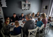 Katja Heimann, her husband and their eleven children sit around a table in their home in Eisemroth, central Germany, Thursday, March 25, 2021. One year into the coronavirus pandemic, Katja Heimann is still trying to keep her spirits up - despite several lockdowns and months of teaching seven of her children in home schooling. (AP Photo/Michael Probst)