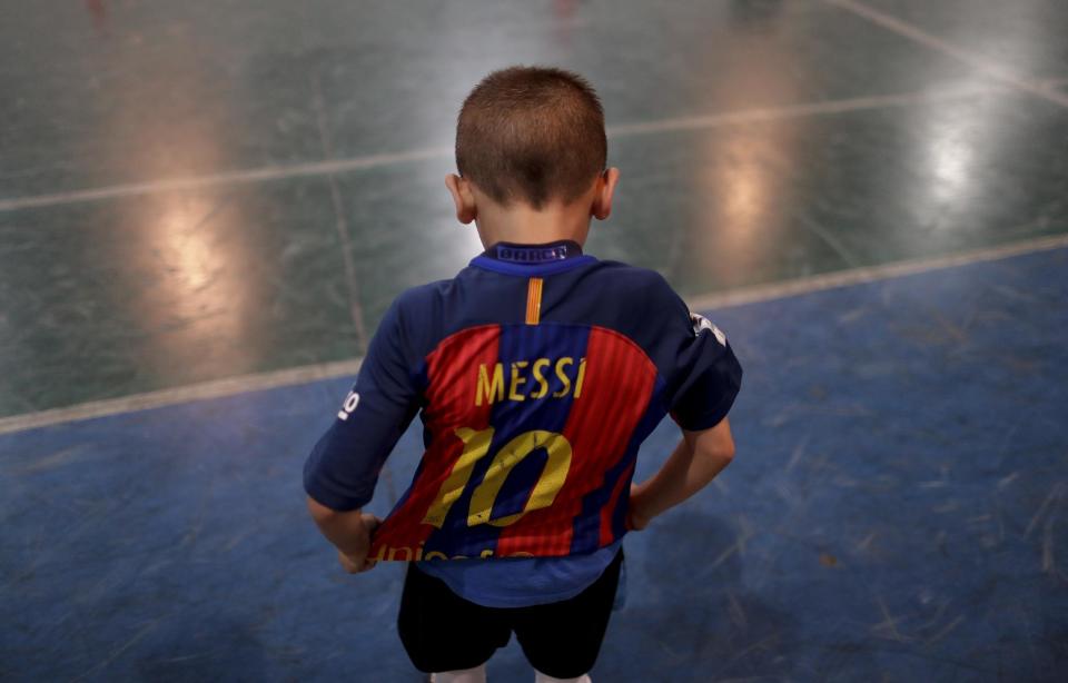 En esta foto del 11 de noviembre de 2016, Benjamín Palandella se pone su jersey del Barcelona, con el número 10 de Messi, después de un entrenamiento en la academia de futbol juvenil Club Social Parque, en un vecindario de clase trabajadora en Buenos Aires, Argentina. Después del juego de entrenamiento, Benjamín siguió pateando el balón, incluso cuando el resto de los chicos se había ido a casa. (AP Foto/Natacha Pisarenko)