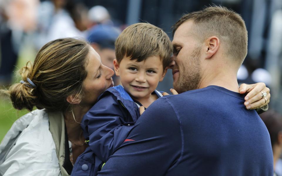 New England Patriots quarterback Tom Brady and his wife Gisele Bundchen embrace their son Benjamin Brady after a joint workout with the Tampa Bay Buccaneers at NFL football training camp, in Foxborough, Mass., Tuesday, Aug. 13, 2013. (AP Photo/Charles Krupa)