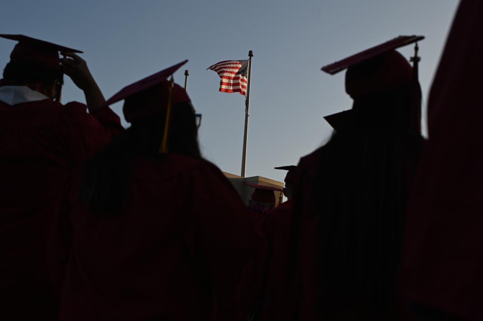 A US flag flies above a building as students earning degrees at Pasadena City College participate in the graduation ceremony, June 14, 2019, in Pasadena, California. - With 45 million borrowers owing $1.5 trillion, the student debt crisis in the United States has exploded in recent years and has become a key electoral issue in the run-up to the 2020 presidential elections. "Somebody who graduates from a public university this year is expected to have over $35,000 in student loan debt on average," said Cody Hounanian, program director of Student Debt Crisis, a California NGO that assists students and is fighting for reforms. (Photo by Robyn Beck / AFP)        (Photo credit should read ROBYN BECK/AFP/Getty Images)