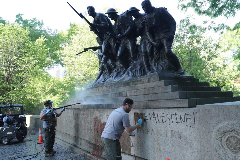 Workers cleaning the spray paint from the base of the memorial. G.N.Miller/NYPost