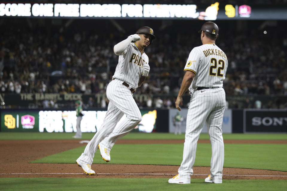 San Diego Padres' Manny Machado, left, rounds third base to greetings from Bobby Dickerson after hitting a three-run home run against the Oakland Athletics during the fifth inning of a baseball game Tuesday, July 27, 2021, in San Diego. (AP Photo/Derrick Tuskan)