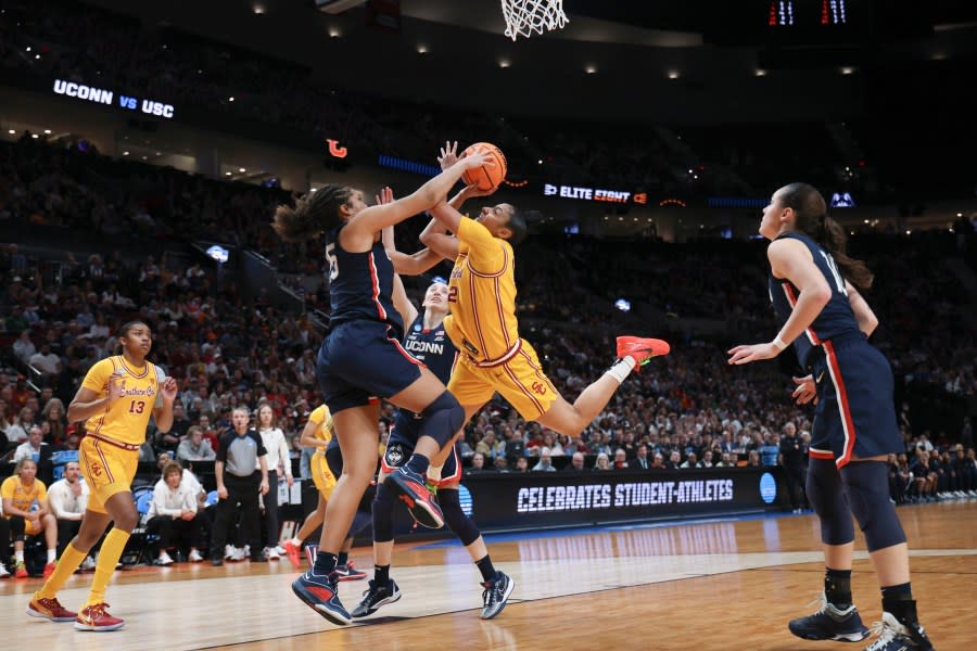Southern California guard JuJu Watkins, center, shoots as UConn forward Ice Brady (25) defends during the second half of an Elite Eight college basketball game in the women’s NCAA Tournament, Monday, April 1, 2024, in Portland, Ore. (AP Photo/Howard Lao)