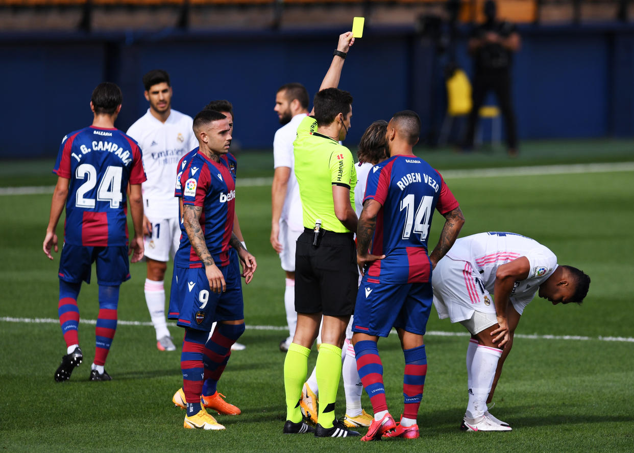 VILLAREAL, SPAIN - OCTOBER 04: Casemiro of Real Madrid is shown the yellow card by Match referee Jose Luis Munuera Montero  during the La Liga Santander match between Levante UD and Real Madrid at Ciutat de Valencia Stadium on October 04, 2020 in Valencia, Spain. Football Stadiums around Europe remain empty due to the Coronavirus Pandemic as Government social distancing laws prohibit fans inside venues resulting in fixtures being played behind closed doors. (Photo by Alex Caparros/Getty Images)