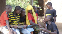 In this undated photo provided by XPRIZE, children in a village in the Tanga region of Tanzania gather to learn from tablets using open-sourced software that would easily be downloaded by illiterate children to teach themselves to read. That's what nearly 200 teams from around the world have spent more than a year in impoverished villages in Tanzania trying to do. The winner of this latest competition for a $10 million XPRIZE for global innovation is being announced Wednesday, May 15, 2019, in Los Angeles. (Courtesy XPRIZE via AP)