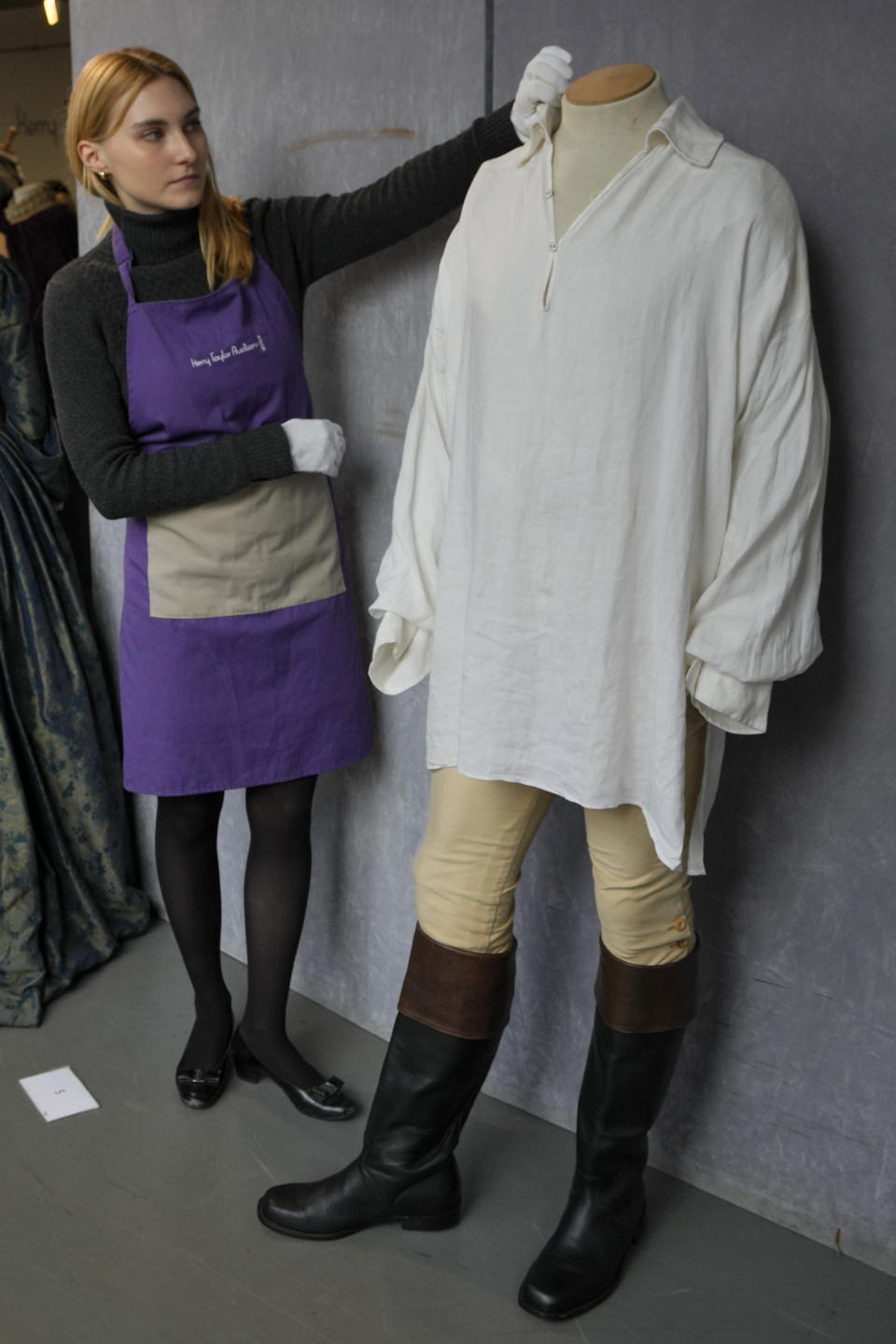 A costume handler arranges Colin Firth's 'wet-shirt' costume as Mr Darcy in the TV series Pride and Prejudice, 1995, at Kerry Taylor Auctions in London, Tuesday, Feb. 27, 2024. The costume estimated at 7,000-10,000 UK Pounds (8,900-12,700 US Dollars) is one of 69 that will be for auction in the Lights Camera Auction event on March 5. The costumes have been donated by Cosprop in support of The Bright Foundation, an arts education charity, established and funded by John Bright, to provide life-enhancing, creative experiences for children and young people facing disadvantage. (AP Photo/Kirsty Wigglesworth)