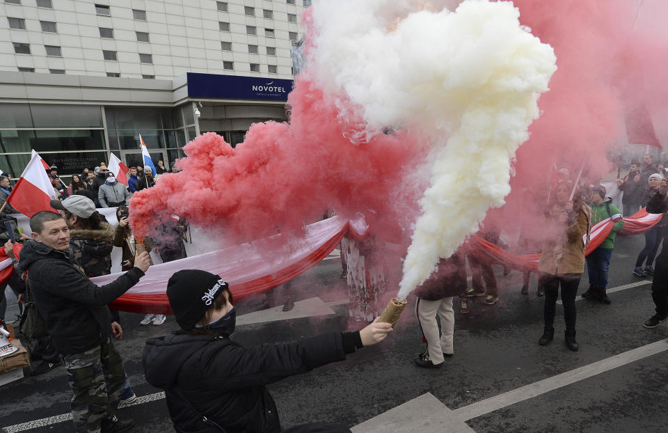 Marchers burn flares as they take part in the annual March of Independence organized by far right activists to celebrate 101 years of Poland's independence marking in Warsaw, Poland, Monday, Nov. 11, 2019. (AP Photo/Czarek Sokolowski)