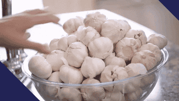 Reaching for garlic in a large glass bowl