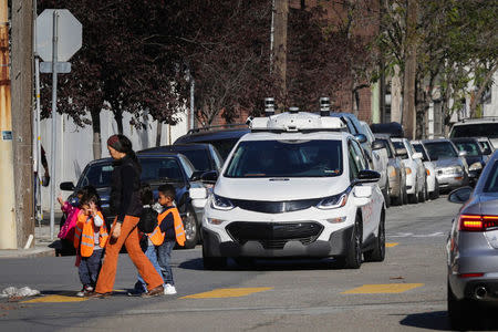 Children pass by a self-driving Chevy Bolt EV car during a media event by Cruise, GM’s autonomous car unit, in San Francisco, California, U.S. November 28, 2017. REUTERS/Elijah Nouvelage