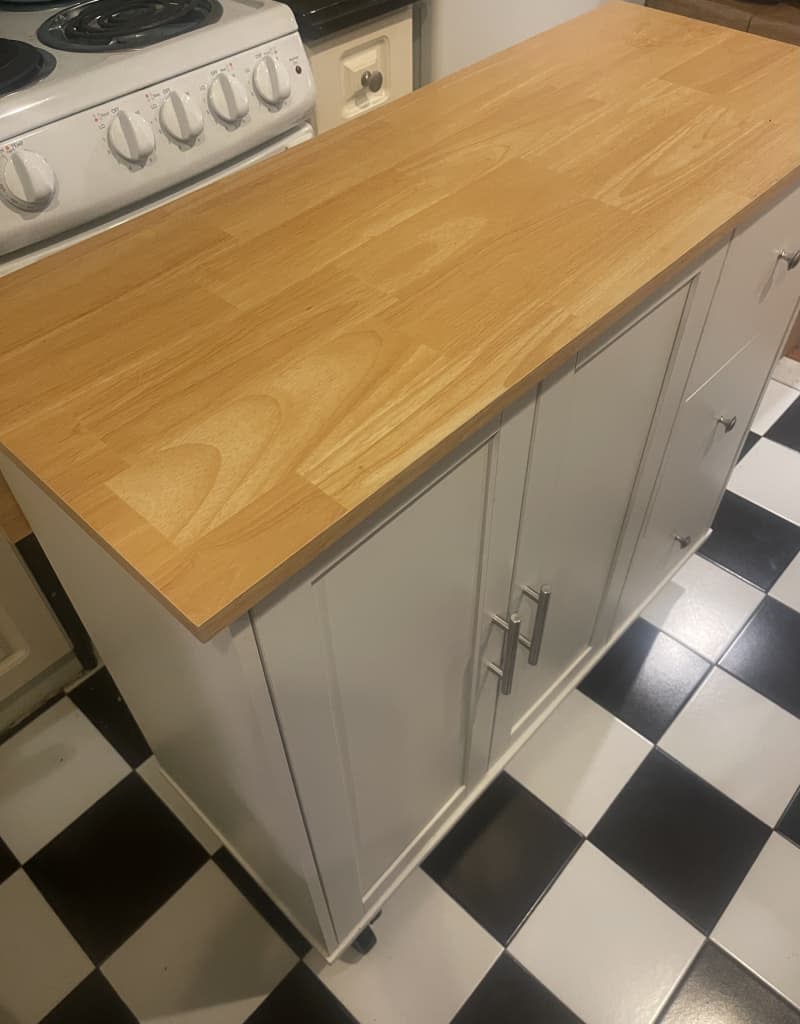 white kitchen island with wood top and cabinets and drawers