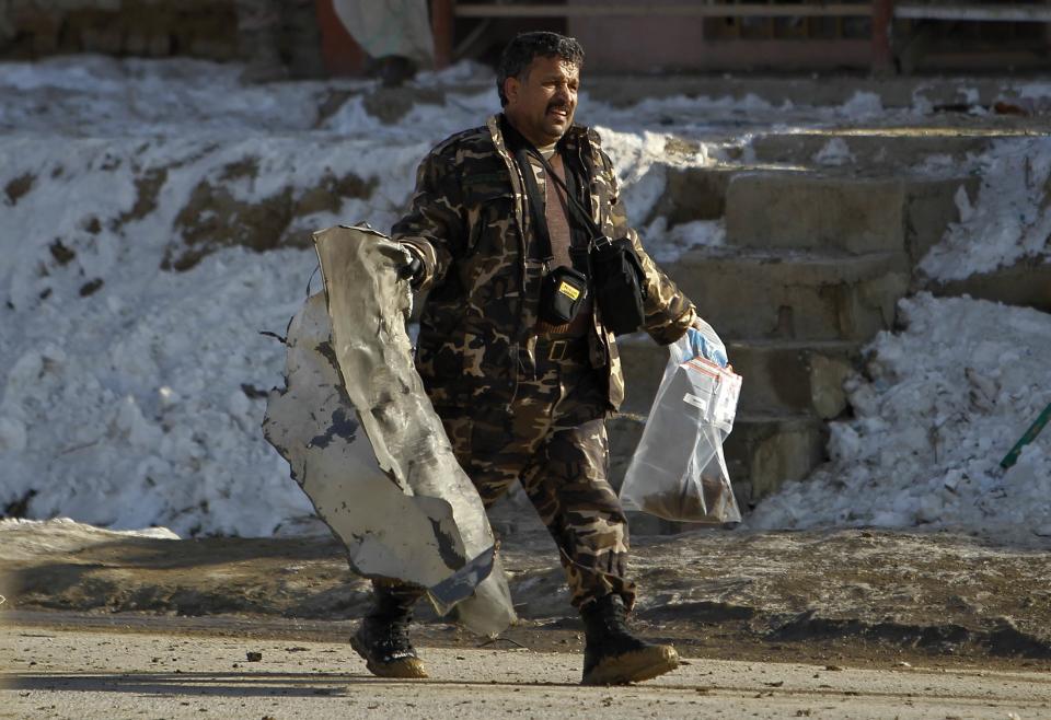 Afghan security personnel removes a piece of wreckage from a car at the site of a suicide car bomb attack in Kabul