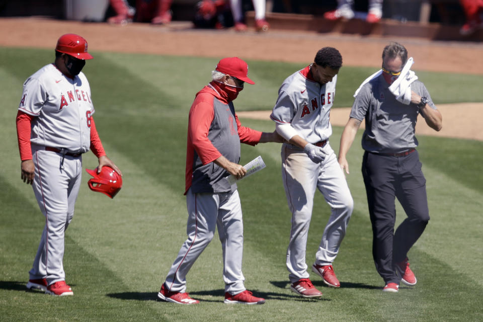 Los Angeles Angels' Andrelton Simmons, second from right, is helped off the field by manager Joe Maddon, second from left, after an injury during the ninth inning of a baseball game against the Oakland Athletics, Monday, July 27, 2020, in Oakland, Calif. (AP Photo/Ben Margot)