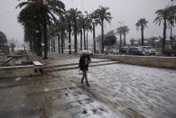 A woman holding an umbrella walks outside Jerusalem's Old City during snowfall in winter December 12, 2013. REUTERS/Darren Whiteside (JERUSALEM - Tags: ENVIRONMENT)
