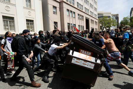 Demonstrators for (R) and against (L) U.S. President Donald Trump push a garbage container toward each other during a rally in Berkeley, California in Berkeley, California, U.S., April 15, 2017. REUTERS/Stephen Lam