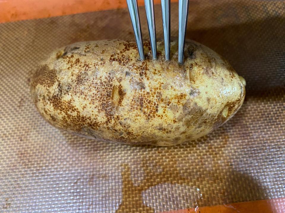 potato being stabbed with a fork on a baking tray