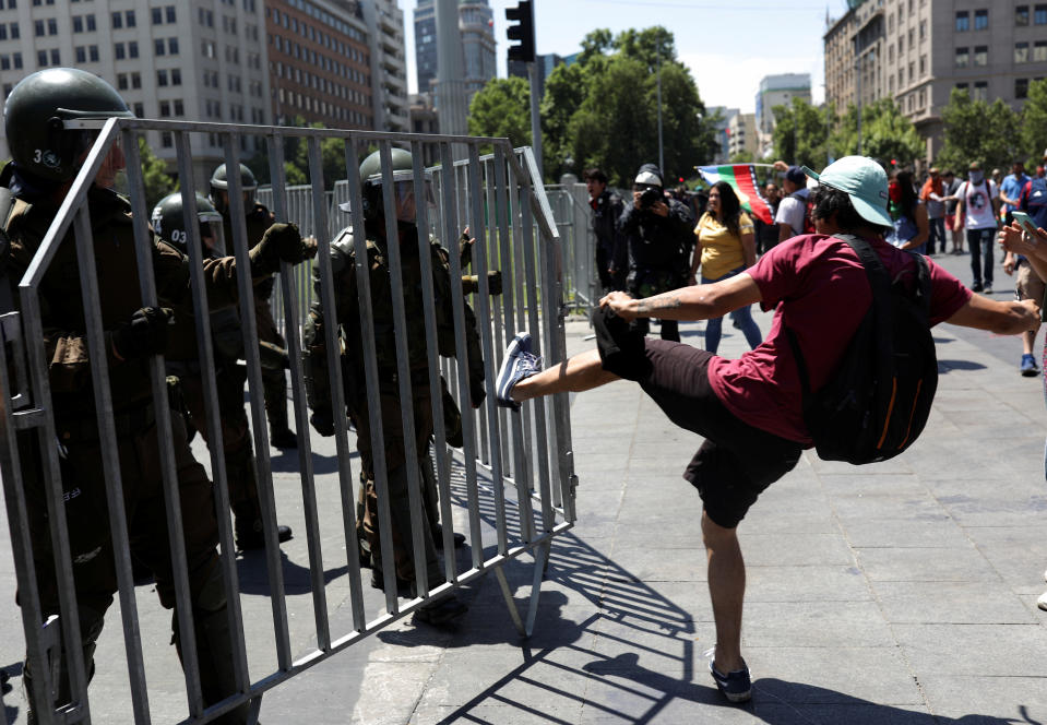 A demonstrator kicks a fence held by police officers during a protest against Chile's government in Santiago, Chile on Oct. 28, 2019. (Photo: Pablo Sanhueza/Reuters)