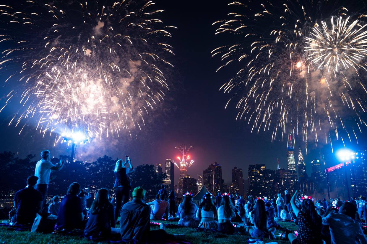 Spectators watch from the Queens borough of New York as fireworks are launched over the East River and the Empire State Building during the Macy's 4th of July Fireworks show on July 4, 2021. 