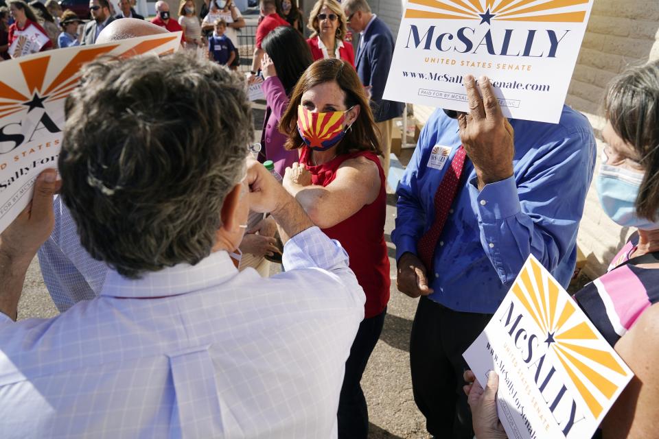 Arizona Republican Sen. Martha McSally, center, gives elbow-bumps as she campaigns at Arizona Republican Party Headquarters, Monday, Nov. 2, 2020, in Phoenix. McSally is running against Democratic candidate Mark Kelly in the election set for Tuesday. (AP Photo/Ross D. Franklin)