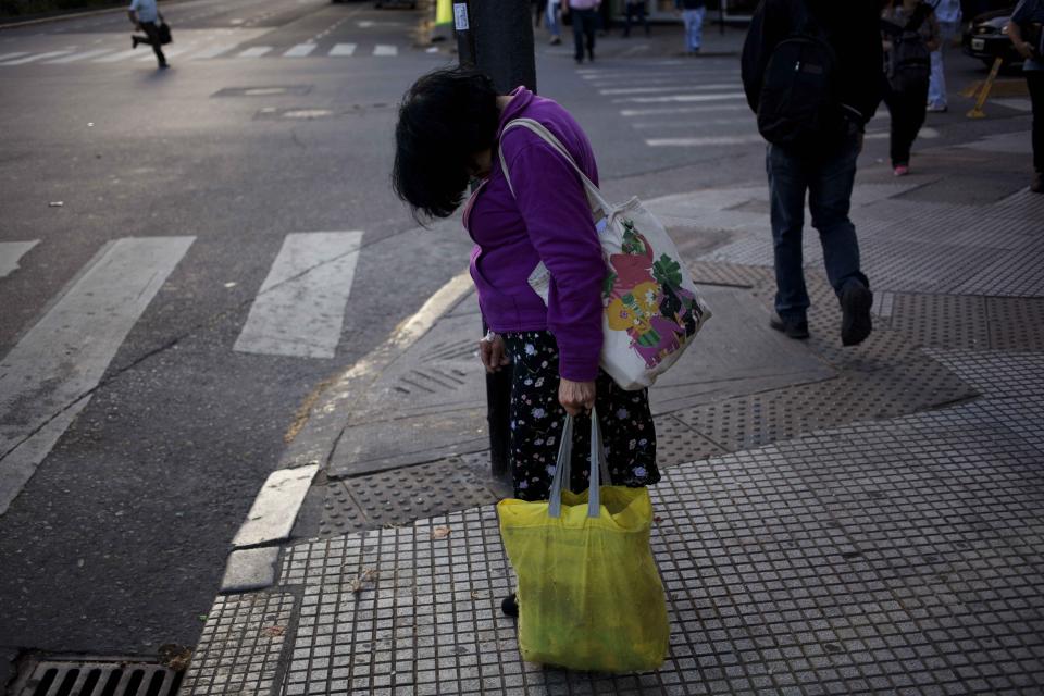 In this Dec. 3, 2013 photo, a woman sleeps while standing on a street corner in Buenos Aires, Argentina. Argentines have suffered through a tough summer, with tropical rain that provided no relief from the heat and humidity, people having to throw out rotten food because of rolling power blackouts and soaring oil and gas prices, all amid rising inflation that is making it ever harder to reach the end of the month. The strain is evident on the faces of subway riders and others making their way home in Buenos Aires, where signs of poverty and decay are ubiquitous just beyond the glamorous streets where tourists go. (AP Photo/Rodrigo Abd)