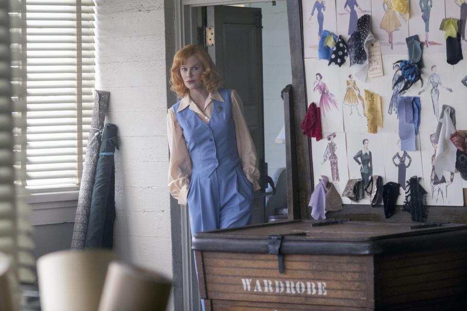 Nicole plays Lucy wearing a pant suit while standing in a wardrobe room