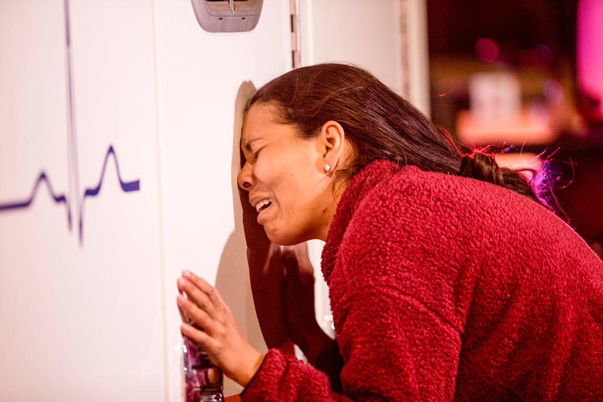Viangly Infante Pedrón llora apoyándose en una ambulancia, en tanto su esposo es atendido por los médicos, después de que se desatara un incendio en las instalaciones de un centro mexicano en Ciudad Juárez, el lunes 27 de marzo del 2023.