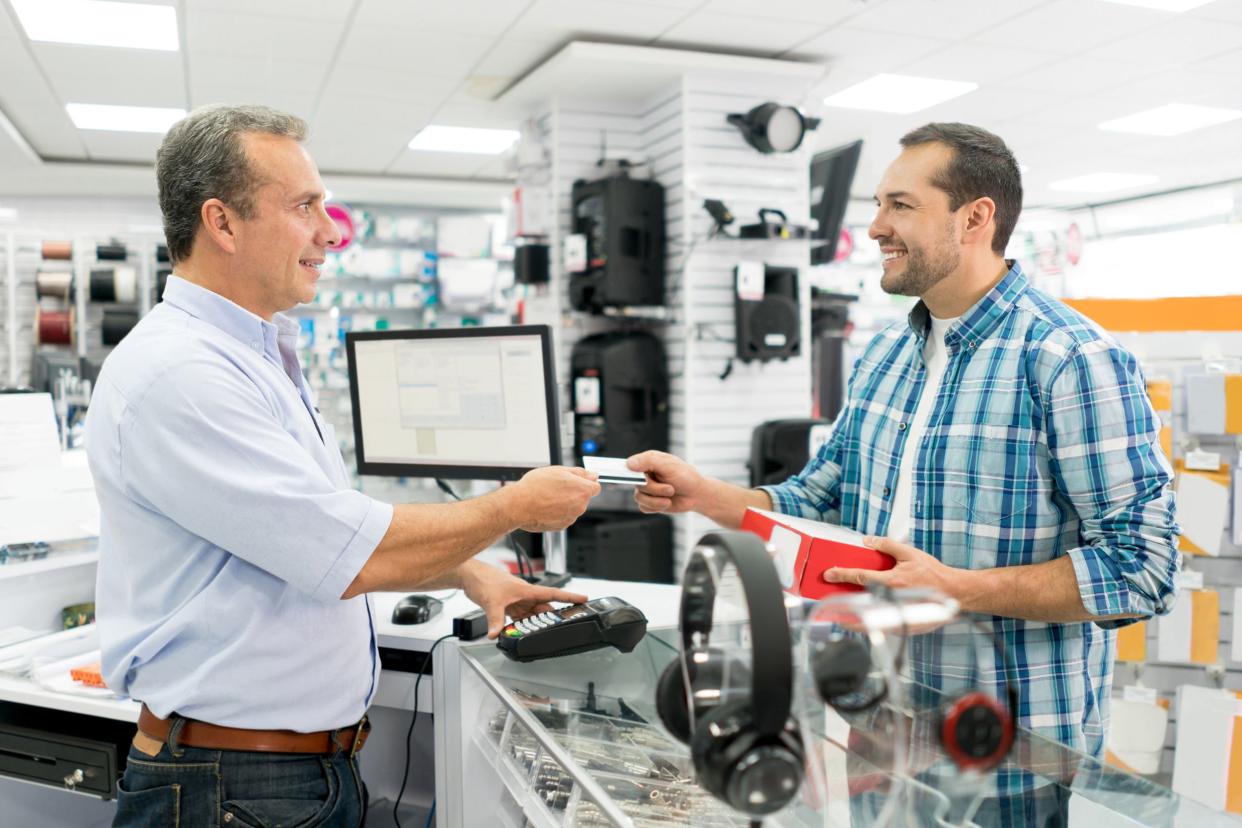 man shopping at a tech store at cashier with credit card purchase