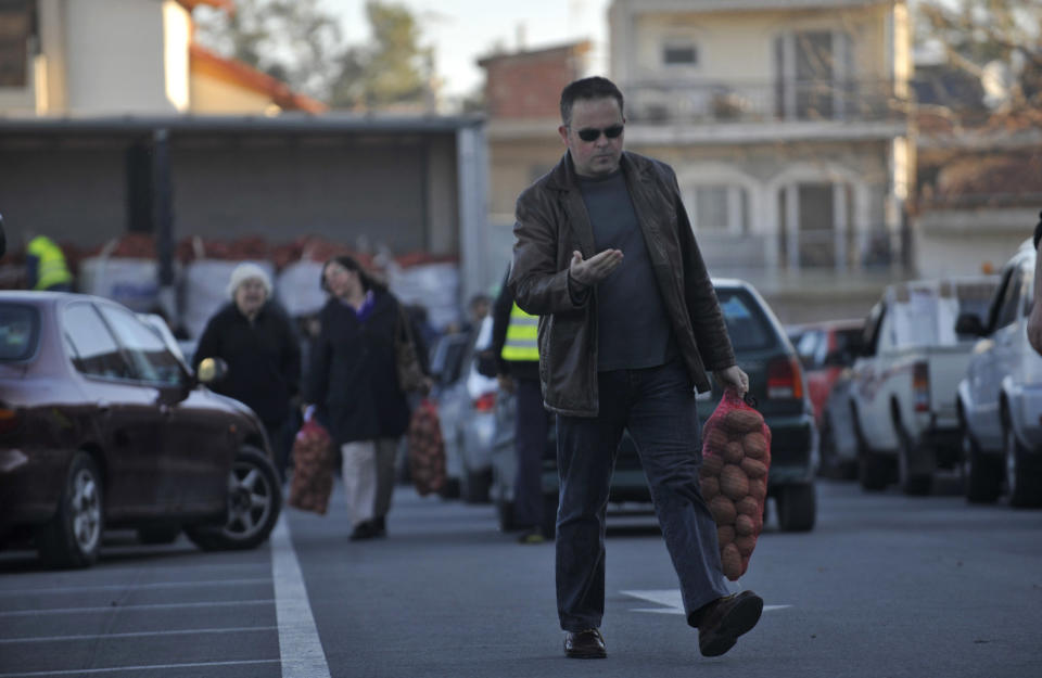 A customer carrying a 10 kg sack of potatoes sold at an extremely low price (euro0.25 per kg) leaves an open market at the northern Greek town of Katerini, Greece on Saturday, Feb. 25 2012. Farmers in northern Greece have joined forces with local residents to provide cheap produce to people whose family budgets have been slashed by the financial crisis, and also to help producers who say they are being squeezed by middlemen. Hundreds of families turned up Saturday in this northern Greek town to buy potatoes at massively reduced prices, sold directly by producers at cost price.. (AP Photo/Nicolas Giakoumidis)