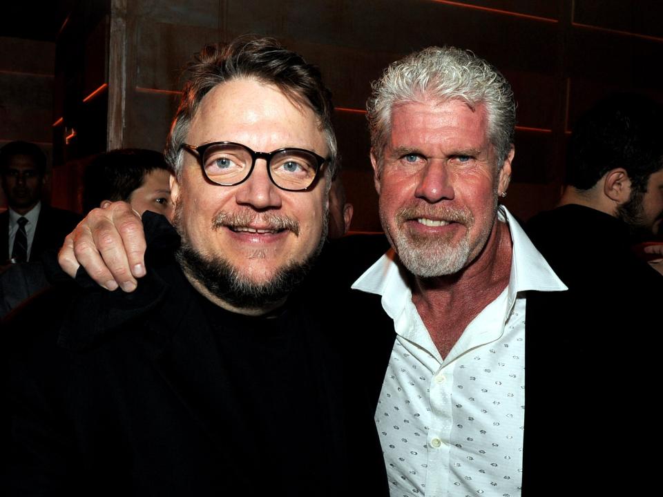 guillermo del toro and ron perlman posing for a photo, with perlman's arm around del toro's shoulders. they're both smiling