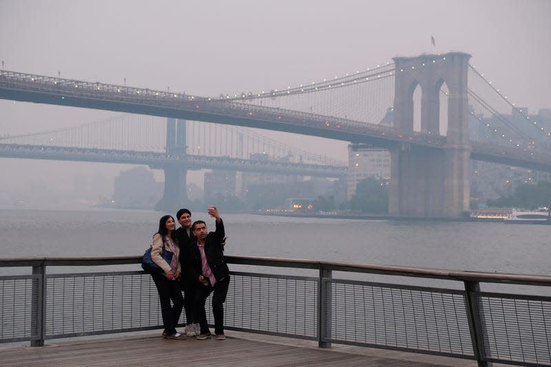 A group takes a selfie with the background of the Manhattan Bridge and Brooklyn Bridge, right, in New York on Wednesday, June 7, 2023 - Photo: Alyssa Goodman (AP)