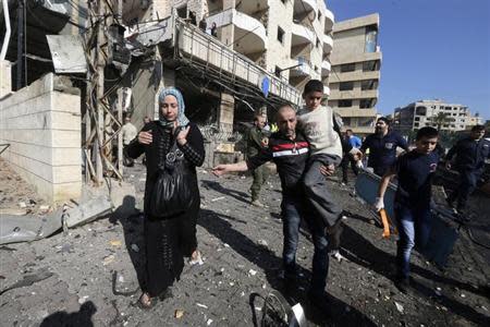 Civilians leave as rescuers rush to the site of an explosion in the southern suburbs of Beirut February 19, 2014. REUTERS/Hasan Shaaban