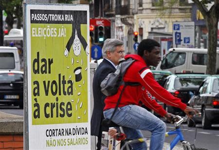 People pass by a political poster reading, "Passos/Toika out. Elections now. Turn the crisis around. Cut the debt and not the salaries", on a street in Lisbon May 7, 2013. REUTERS/Jose Manuel Ribeiro