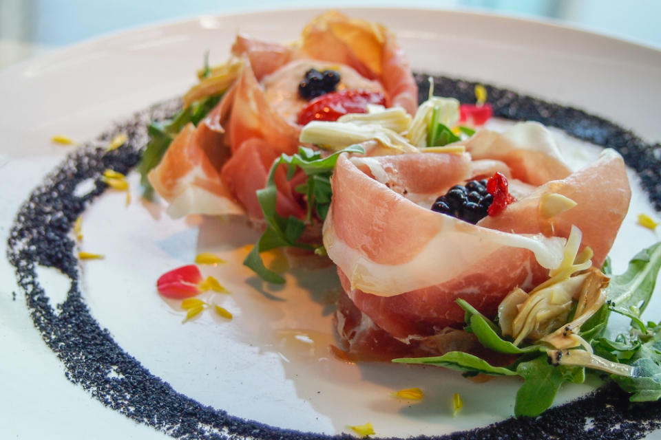 Parma ham wrapped Burrata cheese, topped with aged balsamic caviar, and arugula and artichoke hearts. Photo by writer.