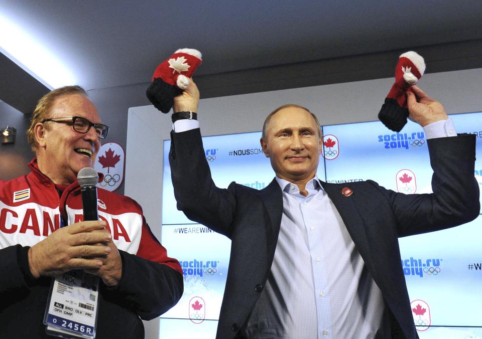 Russia's President Vladimir Putin (R) holds up mittens while standing next to President of the Canadian Olympic Committee Marcel Aubut as he visits Team Canada House at the Olympic Park during the Sochi 2014 Winter Olympics Games, February 14, 2014. REUTERS/Mikhail Klimentyev/RIA Novosti/Kremlin (RUSSIA - Tags: POLITICS OLYMPICS SPORT) ATTENTION EDITORS - THIS IMAGE HAS BEEN SUPPLIED BY A THIRD PARTY. IT IS DISTRIBUTED, EXACTLY AS RECEIVED BY REUTERS, AS A SERVICE TO CLIENTS