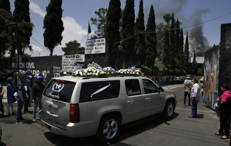In this April 30, 2020 photo, a hearse enters the San Nicolas Tolentino cemetery and crematorium, as smoke rises from the crematorium in the background, in Iztapalapa, Mexico City. Funeral homes and crematoriums in Iztapalapa, a working class borough of 2 million people, are working day and night to manage the surging number of dead in the capital’s hardest hit corner. (AP Photo/Marco Ugarte)