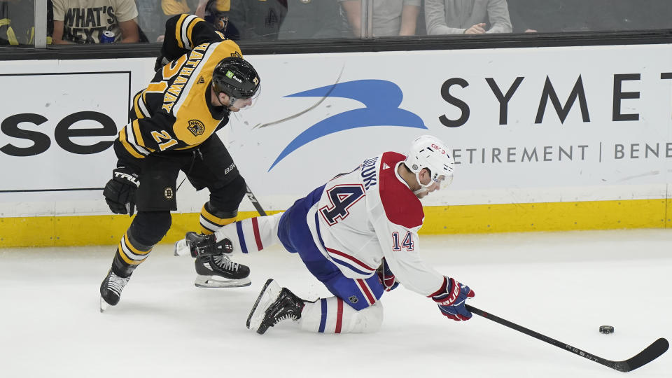 Boston Bruins right wing Garnet Hathaway (21) and Montreal Canadiens center Nick Suzuki (14) pursue the puck during the second period of an NHL hockey game, Thursday, March 23, 2023, in Boston. (AP Photo/Steven Senne)