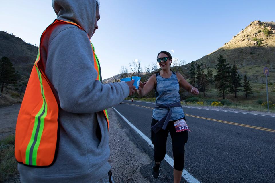 A Fall Equinox marathon runner grabs a water from Severance High School sophomore Robby Peterson on Sept. 22, 2019, during the race in the Poudre Canyon.