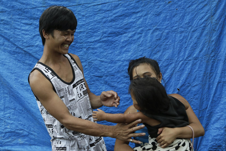 Ronnel Manjares, left, and Trisha May Noche, right, play with their daughter Crystal outside the house of their relative in Tanauan, Batangas province, Philippines, Wednesday, July 15, 2020. Their 16-day-old son Kobe was heralded as the country's youngest COVID-19 survivor. But the relief and joy proved didn't last. Three days later, Kobe died on June 4 from complications of Hirschsprung disease, a rare birth defect. (AP Photo/Aaron Favila)