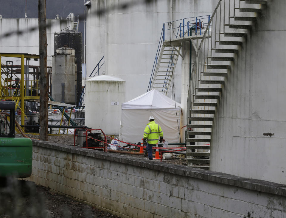 CORRECTS STATE TO W.VA. INSTEAD OF VA. - Work continues around storage tanks at Freedom Industries storage facility in Charleston, W.Va., Monday, Jan. 13, 2014. The ban on tap water for parts of West Virginia was lifted on Monday, ending a crisis for a fraction of the 300,000 people who were told not to drink, wash or cook with water after a chemical spill tainted the water supply. Gov. Earl Tomblin made the announcement at a news conference, five days after people were told to use the water only to flush their toilets. (AP Photo/Steve Helber)