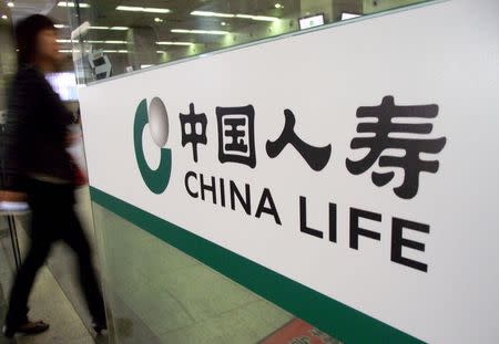 A woman walks past a door with a logo of China Life insurance, in Nanjing, Jiangsu province, May 6, 2013. REUTERS/China Daily