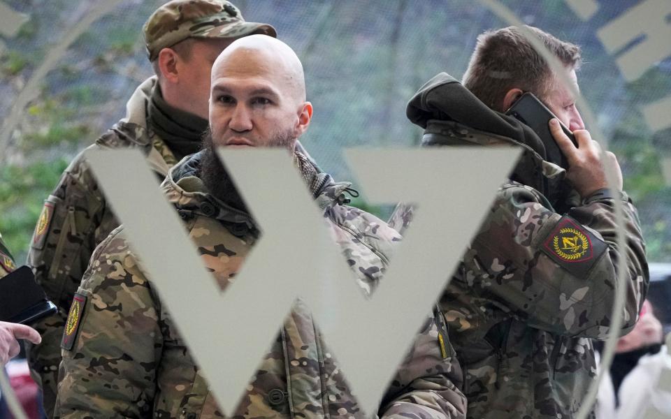 FILE - Visitors wearing military camouflage stand at the entrance of the 'PMC Wagner Centre', which is associated with businessman and founder of the Wagner private military group Yevgeny Prigozhin, during the official opening of the office block during National Unity Day, in St. Petersburg, Russia, on Nov. 4, 2022. Russia's Wagner Group, a private military company led by Yevgeny Prigozhin, a rogue millionaire with longtime links to Russia's President Vladimir Putin, has played an increasingly visible role in the fighting in Ukraine. (AP Photo, File) - AP