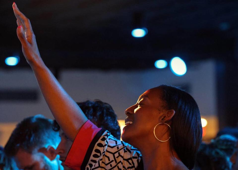 A congregant hold her hand up while worshiping at a VOUS service on Palm Sunday in Miami Gardens.