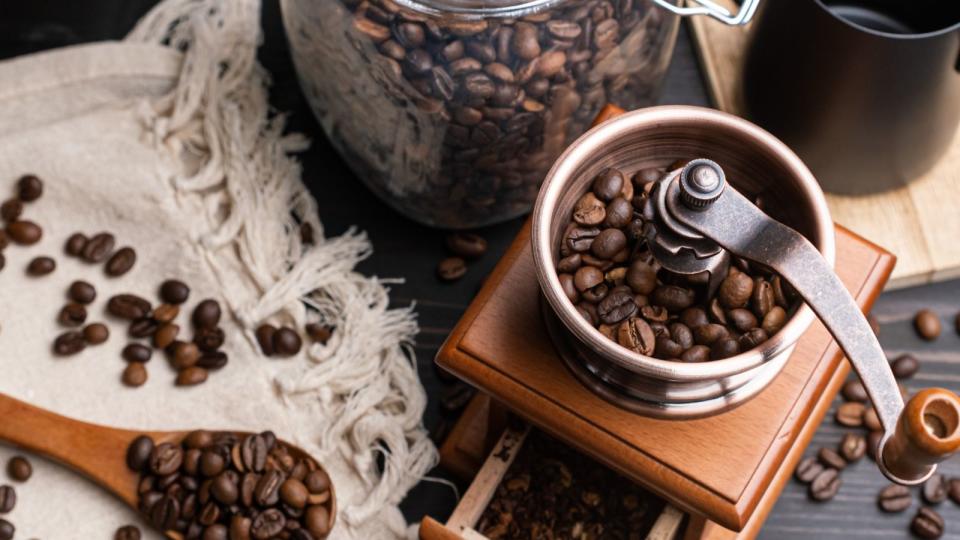 A coffee grinder with coffee beans around it