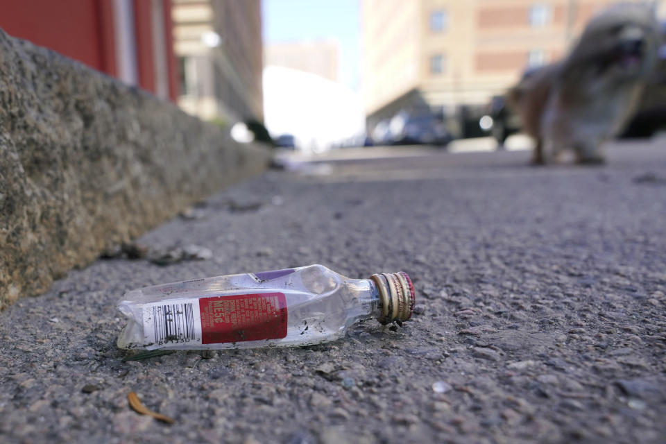 An empty miniature bottle that once contained liquor rests on a street near a sidewalk, Monday, April 3, 2023, in Boston. A Boston city councilor has proposed barring city liquor stores from selling the single-serve bottles that hold 100 milliliters or less of booze both as a way to address alcohol abuse and excessive litter. (AP Photo/Steven Senne)