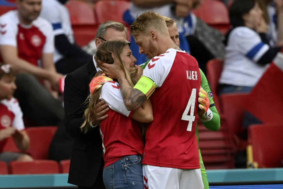 El capitán de la selección de Dinamarca, Simon Kjaer consuela a la novia de Christian Eriksen, quien se desvaneció durante un partido de la Eurocopa ante Finlandia, el sábado 12 de junio de 2021, en Copenhague (Stuart Franklin/Pool via AP)