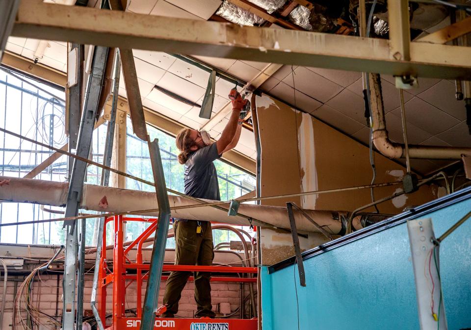 Chad Fleming, of Here to Help and Haul, clears out debris from the ceiling of the old Brown's Bakery located In Midtown.