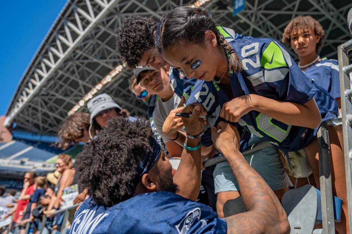 Seattle Seahawks running back Rashaad Penny signs Vivian Snider’s jersey after their mock game in Lumen Field on Saturday Aug. 6, 2022