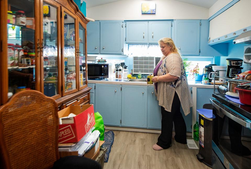 Karen McDonald, enjoys the Antique blue kitchen inside her mobile home in Falls Township, on Monday, Nov. 8, 2021. Above is a flower painting, one of many by McDonald.