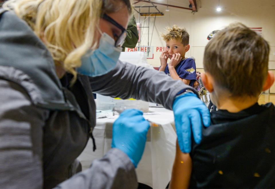 Eli Bryant, age 8, watches with trepidation as his brother Drew receives his flu and COVID vaccinations at the Alluvion Health vaccine clinic on Wednesday evening at Paris Gibson Education Center.