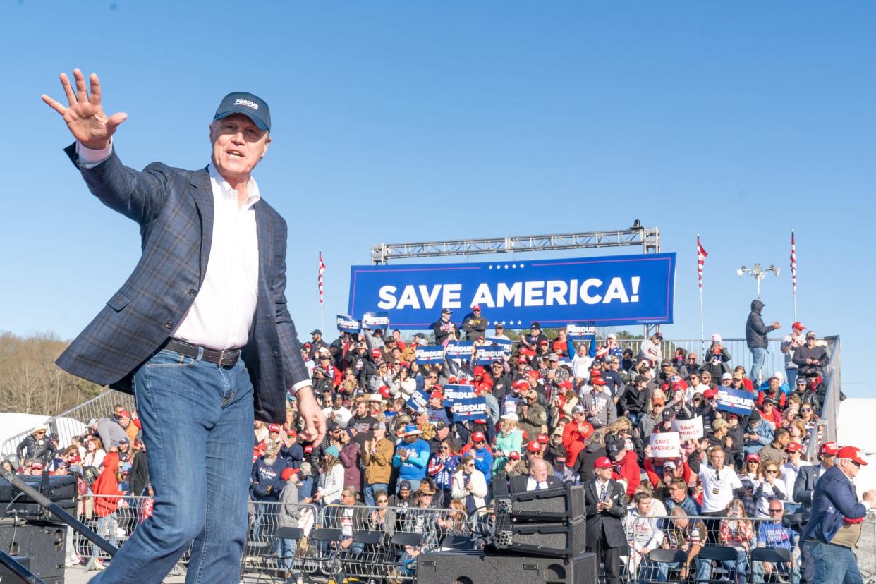 Georgia gubernatorial hopeful David Perdue, his right hand extended as he waves to Trump supporters, takes the stage at a "Save America" rally on March 26, 2022 in Commerce, Georgia.